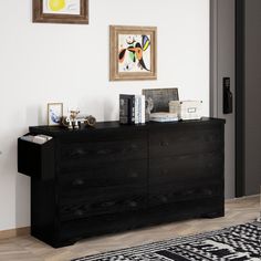 a black dresser sitting in a living room next to a painting on the wall above it