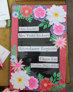 a pink and black sign with flowers on it sitting next to some paper work items