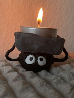 a candle that has been placed on top of a bed with eyes drawn on it