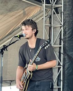 a man standing on top of a stage holding a guitar