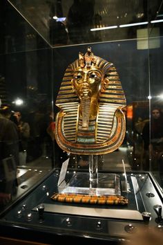 an egyptian mask on display in a glass case