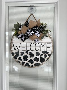 a welcome sign hanging on the side of a door with black and white decorations around it