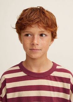 a young boy with freckles on his face is posing for the camera while wearing a striped shirt