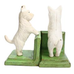 two white cats standing on their hind legs in front of a green bookends