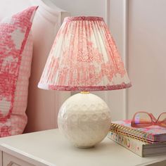 a white lamp sitting on top of a table next to a book and eyeglasses