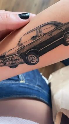 a woman's arm with a black and white tattoo of a car on it