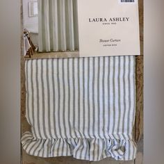 an open box on top of a bed next to a striped curtain and window valance