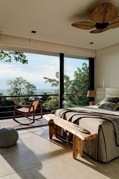 a bedroom with a bed, chair and table in front of a large window overlooking the ocean