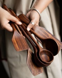 a woman holding wooden utensils in one hand and spoons in the other