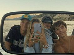 three people taking a selfie in the side mirror of a car while on a boat