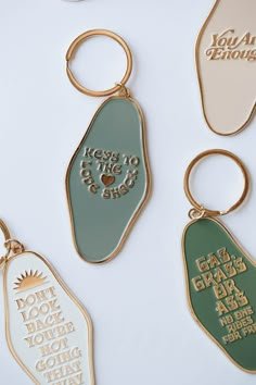 four key chains with different designs on them, one is gold and the other is green