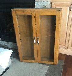 a wooden cabinet sitting in front of a fireplace