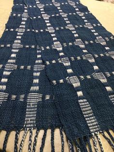 a blue and white blanket sitting on top of a bed