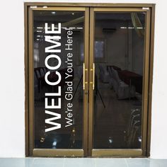 an open glass door with the words welcome on it's side and chairs in the background