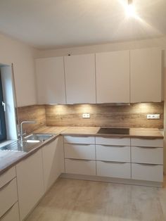 an empty kitchen with white cabinets and wooden counter tops, is shown in this image