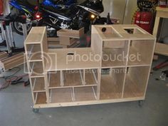 a motorcycle is parked in the garage next to some wooden shelves and other items on wheels