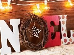 the word noel spelled out in wood letters with christmas lights strung around it and a wreath on top