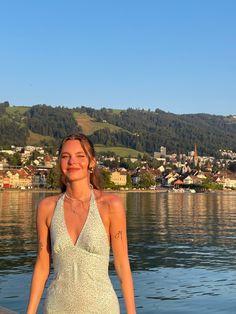 a woman standing on the edge of a body of water in front of a town