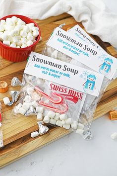 some marshmallows are sitting on a cutting board next to a bowl of candy