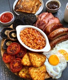 a breakfast plate with eggs, bacon, beans, toast and sausages on it