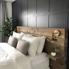 a bed with white linens and pillows in a bedroom next to a potted plant