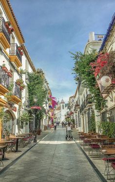 an empty street with tables and chairs lined up along the side of each other in front of buildings