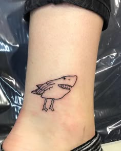 a small shark tattoo on the ankle that looks like it has been placed on someone's leg