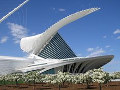 the exterior of a modern building under a blue sky with white clouds in the background