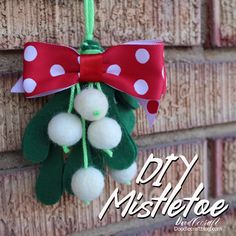 a red and white polka dot bow hanging on a brick wall with pom - poms