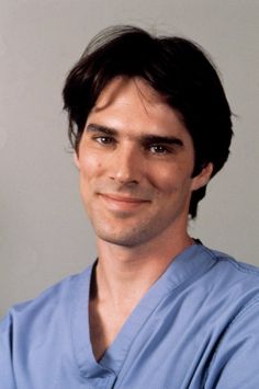 a man in scrubs is smiling at the camera