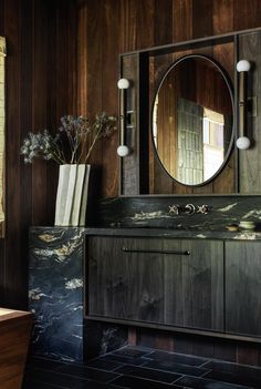 a bathroom vanity with a mirror above it and vase on the counter next to it