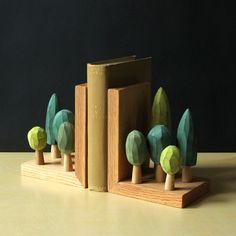 three books are stacked on top of each other in the shape of trees and leaves