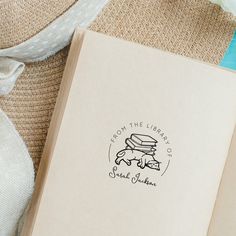 an open book sitting on top of a table next to a hat and some flowers