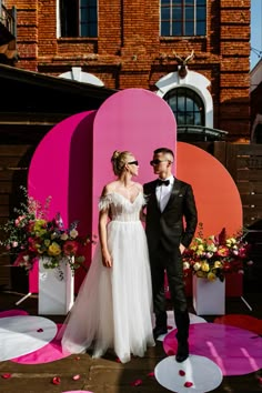 a bride and groom standing in front of a giant heart shaped sign at their wedding