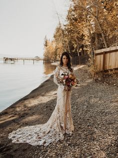 a woman in a wedding dress standing by the water