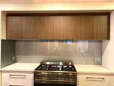 a stove top oven sitting inside of a kitchen next to white cupboards and drawers