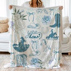 a woman holding up a white blanket with blue images on it