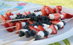 strawberries and blueberries are arranged on skewers for an appetizer