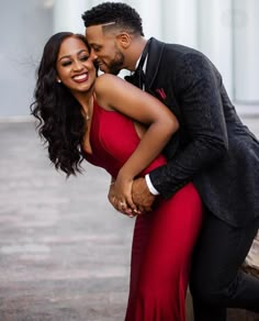 a man and woman hugging each other in front of a building