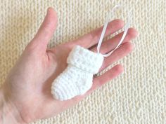 a hand holding a small white crocheted object in it's left palm