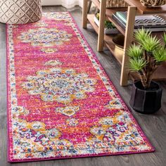 a pink and yellow rug with an ornate design on the floor in a living room