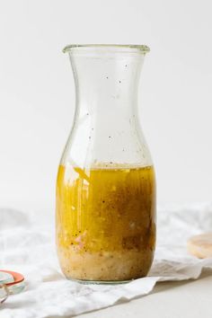 a glass vase filled with liquid sitting on top of a white table cloth next to spoons