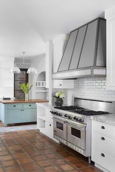 a kitchen with an oven, stove and counter tops in the middle of it's tile flooring