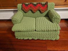 a crocheted green couch with a red pillow on it