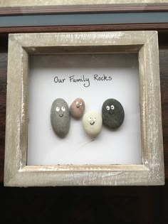 three rocks in a frame with the words our family rocks written on them and faces drawn on them