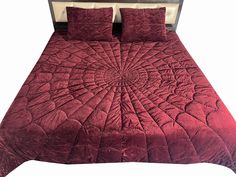 a bed with red comforter and pillows on it