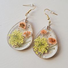 the dandelions are hanging from tear shaped glass earrings