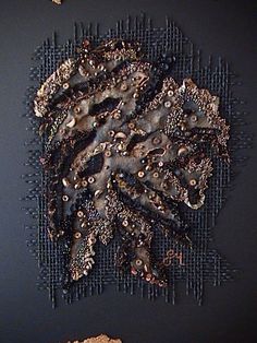 a piece of art made out of wire and beads on a black surface with other items around it