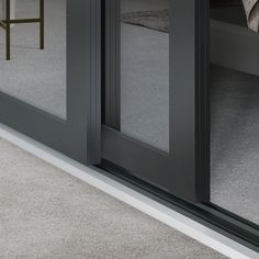 the reflection of a bed in an open door on carpeted floor next to a chair