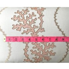 a pink and white pillow with a measuring tape in front of it that has corals on it